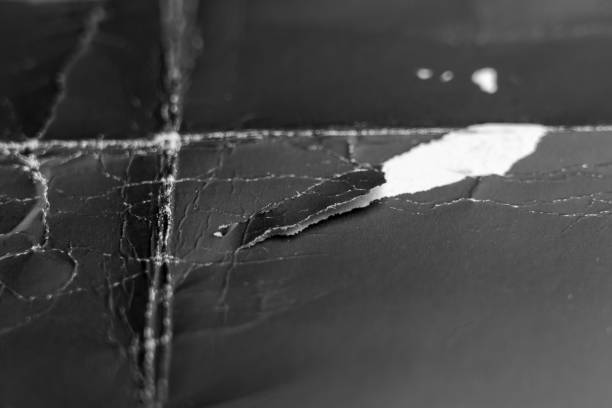 istock Torn piece of old black paper. White underlayer 2202089838