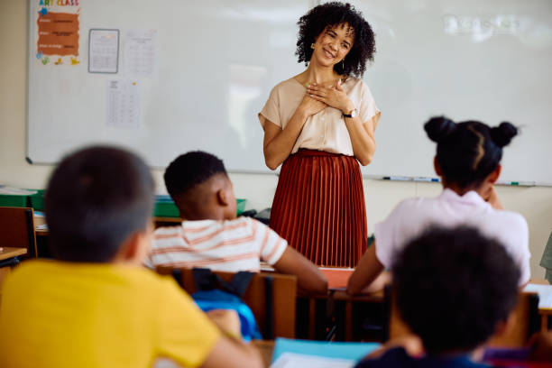 istock Elementary school teacher at front of class smiling with hands on chest, gratitude, emotion, pride 2202092228