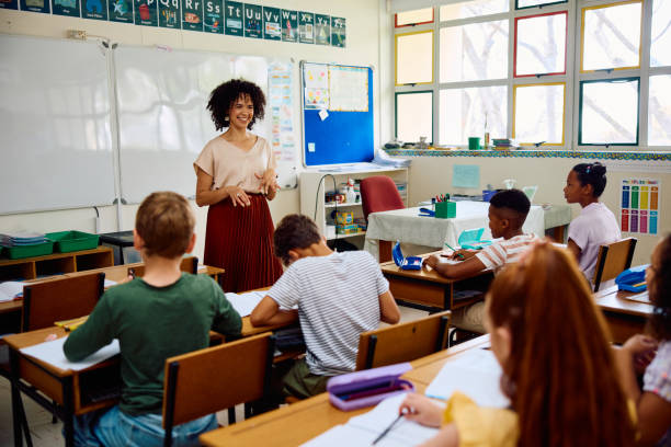 istock Cheerful elementary school teacher at front of class talking to children 2202092661