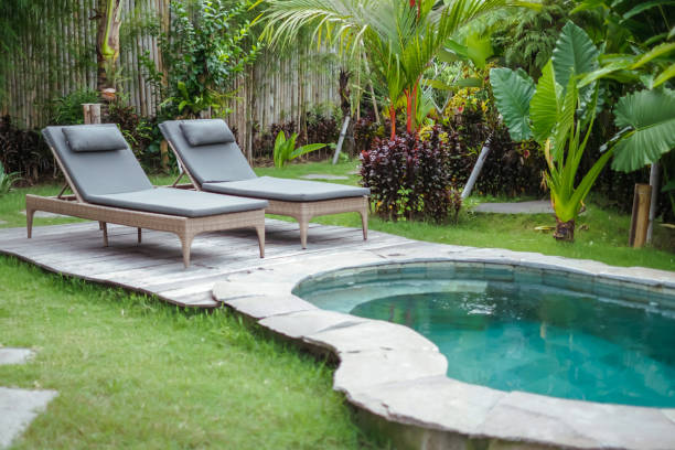 Shot of serene outdoor setting featuring two sun loungers by a private plunge pool, surrounded by lush tropical greenery for ultimate relaxation. Concept: luxury resort, private villa, tropical retreat, relaxation, spa getaway, outdoor pool, vacation vibes, nature escape, tranquil ambiance, summer holiday