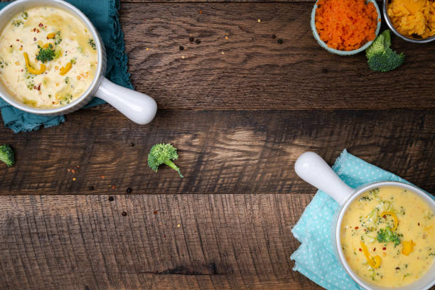 istock Creamy, Broccoli cheddar soup in white bowls with handle on a walnut table background with blue napkins. 2202093696