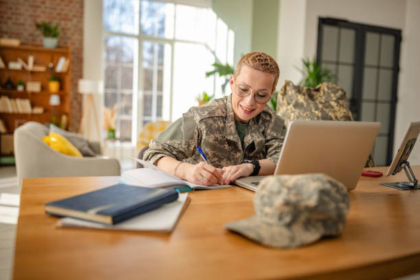 istock Young woman in military uniform working from home, engaged in paperwork and using technology in a modern office setting 2202097163