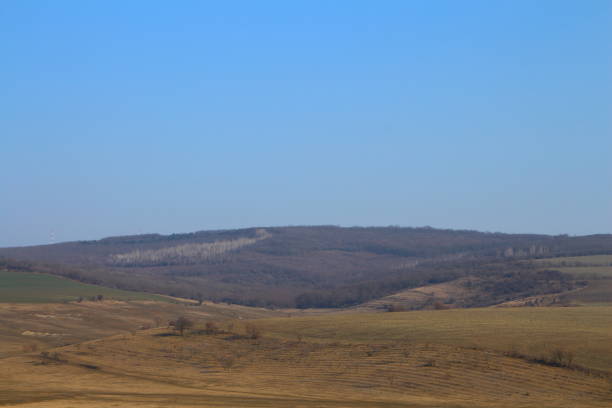 A field with a hill in the background. Outdoor. Sky. Mountain. Grass. Nature