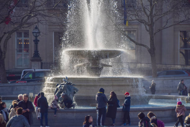 London, UK - February 18 2025: people walk past the fountain in Trafalgar Square on a sunny day