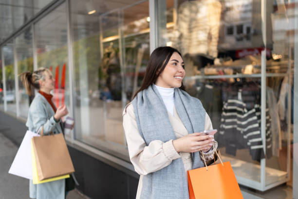istock Young woman with shopping bags using phone 2202099094