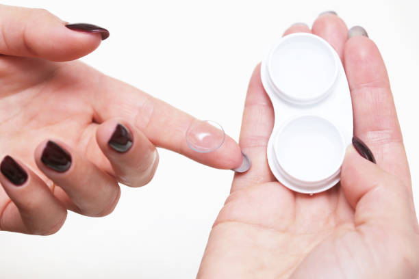 istock Woman handling a contact lens with care. Cleaning process using lens liquid. 2202101808