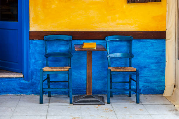 Vividly painted cafe exterior with a yellow wall and blue accents, exuding Mediterranean charm and inviting atmosphere. Outdoor seating enhances the casual and welcoming vibe of this picturesque urban setting.