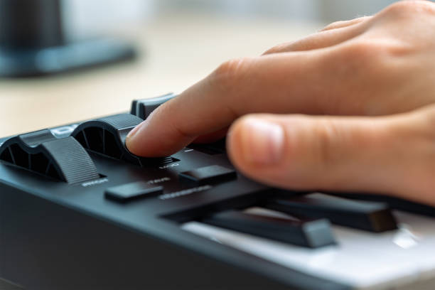 istock Woman playing MIDI keyboard with control knobs and pads, close-up. 2202105263