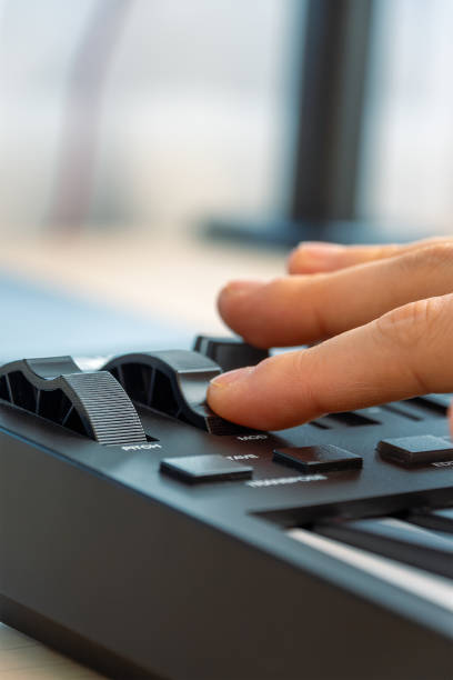 istock Woman playing MIDI keyboard with control knobs and pads, close-up. 2202105297