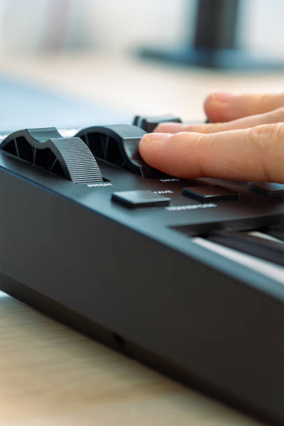 istock Woman playing MIDI keyboard with control knobs and pads, close-up. 2202105309