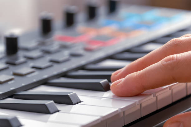 istock Woman playing MIDI keyboard with control knobs and pads, close-up. 2202105417