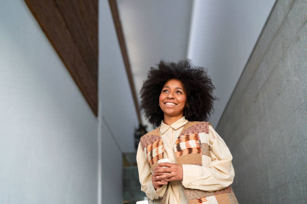 istock Young manager holding a coffee cup, looking up and smiling while walking in a modern office 2202106734