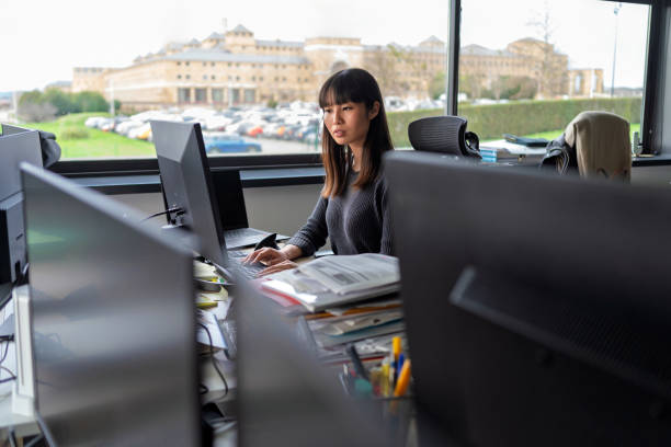 istock Focused businesswoman concentrating while working at a computer in a busy, modern office environment filled with natural light 2202106788