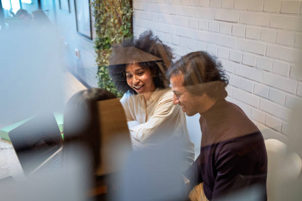 Professional team collaborating, discussing project details on laptop, working together in contemporary workspace