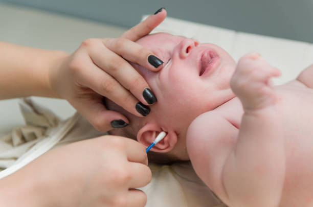 istock Mother cleaning baby's ear with cotton swab 2202111410
