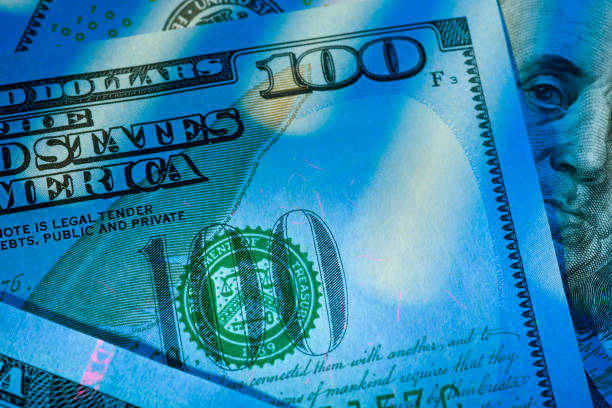istock Hundred US dollar bills glow under ultraviolet light. Verifying the authenticity. 2202114203