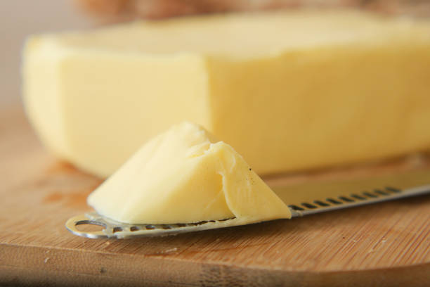 A generous chunk of creamy butter sits invitingly beside a knife on a sturdy cutting board