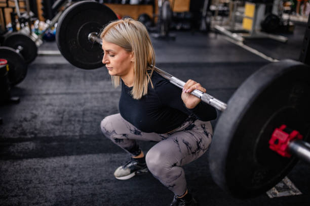 istock Focused Strength Training: Woman Squatting Barbell 2202117896