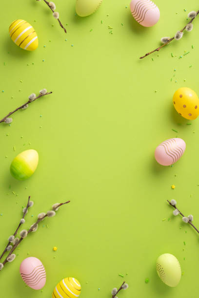 istock Colorful vertical painted eggs and branches arranged on green backdrop, symbol of Easter 2202118168