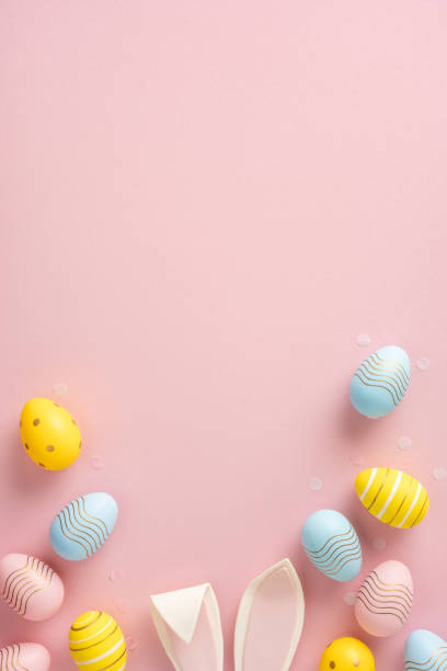 istock Decorative Easter eggs and bunny ears placed artistically on a pink minimalistic background 2202118193
