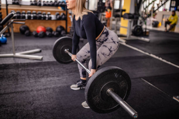 istock Focused Woman Lifting Barbell in Gym Setting 2202119562