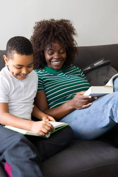 Happy mother and son enjoying quality time together, reading books on a comfortable sofa in their living room