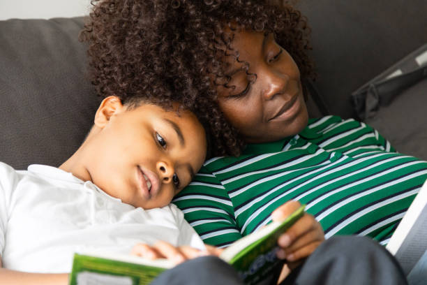 istock Mother and son reading a book together on sofa at home 2202121224