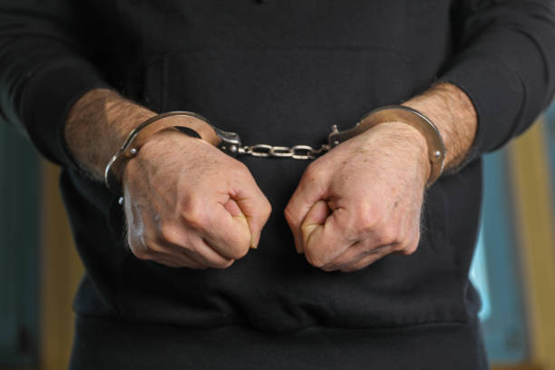 A middle-aged man with handcuffs on his wrists, bribery, corruption, fraud.