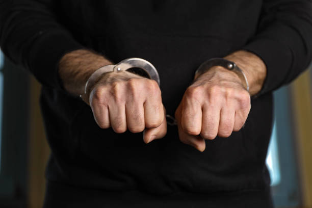 A middle-aged man with handcuffs on his wrists, bribery, corruption, fraud.