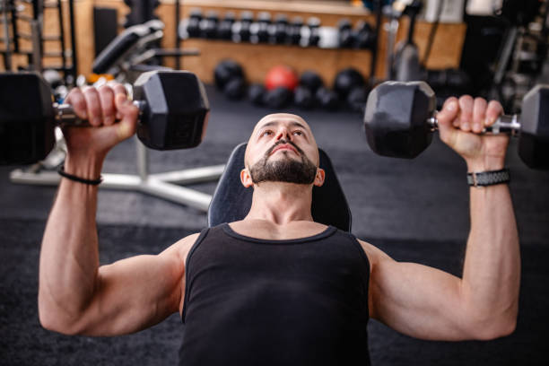 istock Man Lifting Dumbbells in a Gym Setting 2202124075