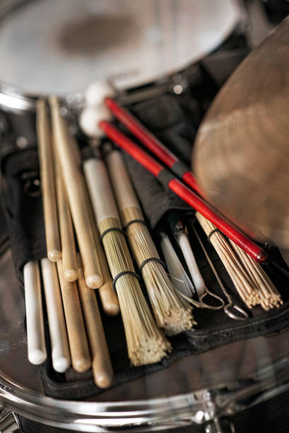 Various drumsticks, jazz brushes, brooms, drum brushes made of Sorghum grass are lying on a floor tom in a recording studio.