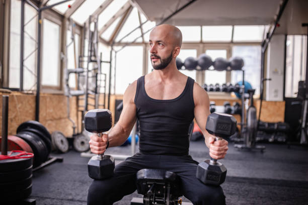 istock Man Lifting Dumbbells in Modern Gym Setting 2202124397