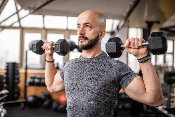 istock Man Lifting Heavy Dumbbells in Modern Gym 2202124602