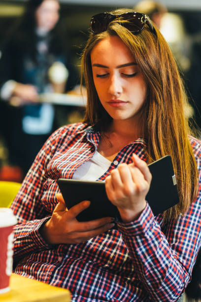 istock Young woman in cafe reading e-book 2202127814