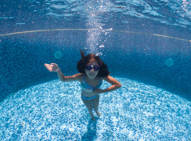 istock Smiling young girl diving underwater. 2202129552