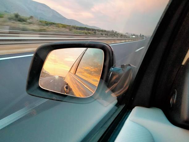 istock A reddish dawn sky reflected in the rearview mirror of a car 2202129624