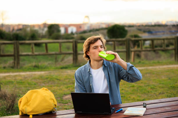 Young traveler drinking water while working outdoors, Madrid, Spain.