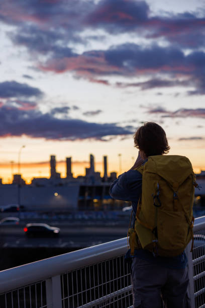 istock Backpacker admiring Madrid's skyline from a bridge over the highway at sunset. Spain 2202131140