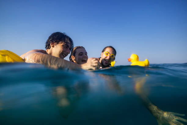 Floating on the yellow mattress in the sea while playing with a rubber duck toy