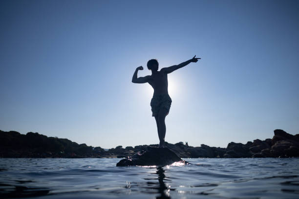 A young man flexing his muscles and posing on the beach