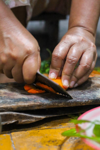 istock woman's hand cutting carrots on a wooden board 2202134497