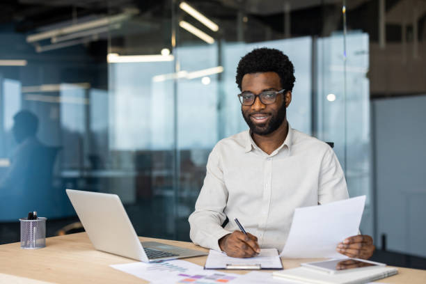 istock Portrait g accountant financier, man behind paperwork smiling and looking at camera, a businessman in a shirt holding a contract and a tax form in his hands, filling out a balance sheet and report 2202134948