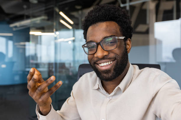 istock Businessman smiling and looking into smartphone camera, man using app on phone for video call, company employee at workplace inside office 2202135788