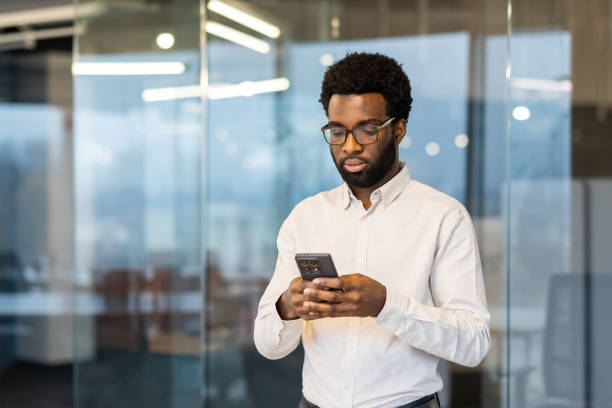 istock Serious focused man standing inside office with phone in hand, businessman typing text message thoughtfully, employee in business clothes using app at workplace 2202135805