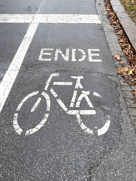 istock Bicycle lane end marking on wet asphalt with autumn leaves 2202137444