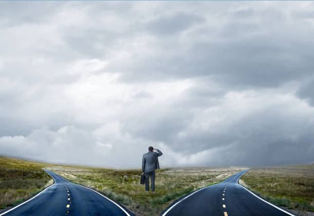 istock Businessman Standing At Fork In Road Looking Into The Distance 2202137779