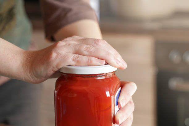istock Open Stuck Jar. Problem when working with tightly closed Jars with Pickled. Woman Opening Glass Jar with preserved tomatoes 2202138102