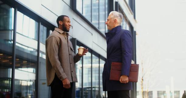 istock Two men shake hands in informal communication, standing outdoors 2202139650