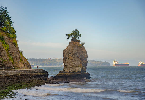 View of Siwash Rock and the seawall with one person walking, Stanley Park, Vancouver, BC