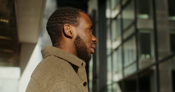 istock A young African-American man is standing sideways to the camera and talking 2202139931